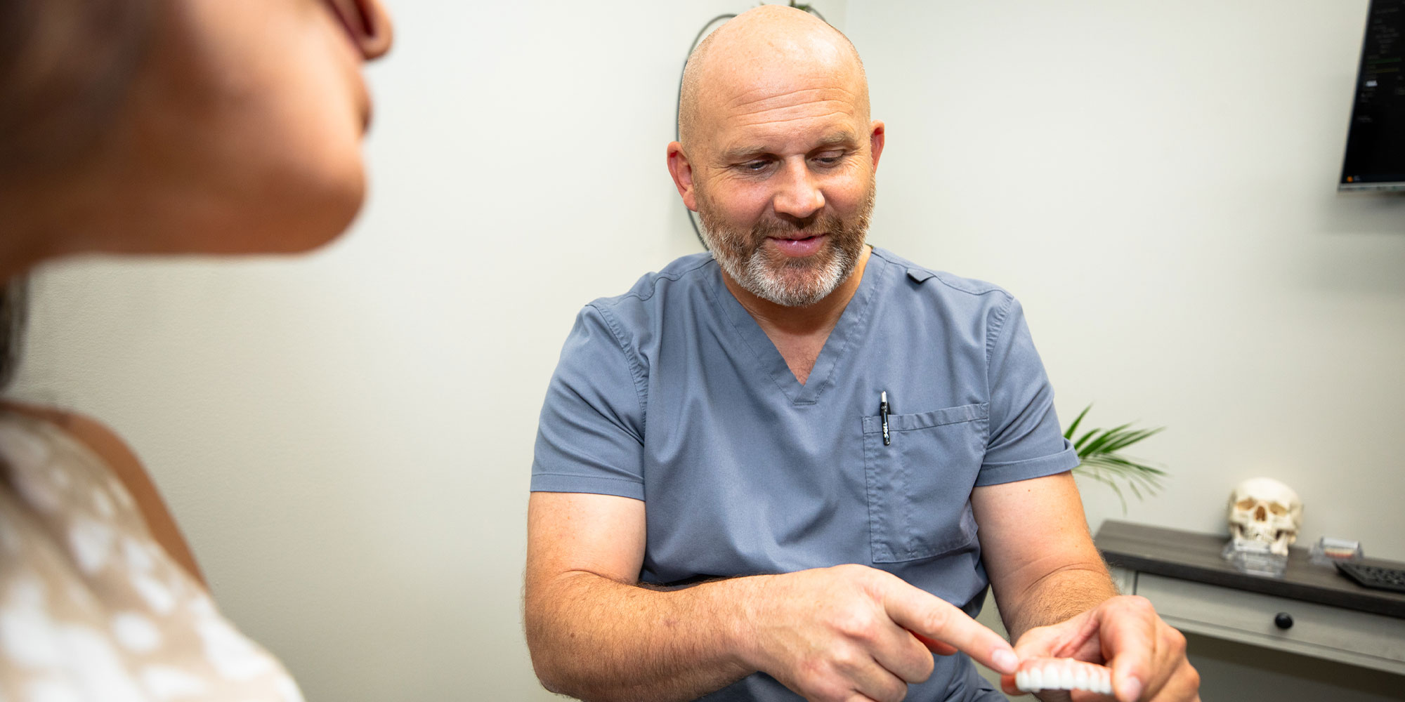 doctor showing patient implant model within the dental center