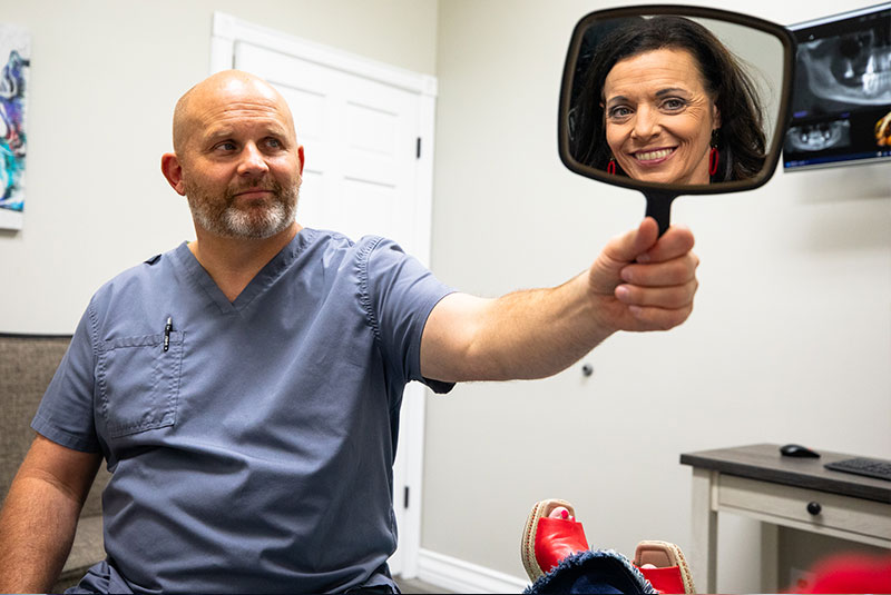 doctor showing their patient a mirror to smile after their dental procedure